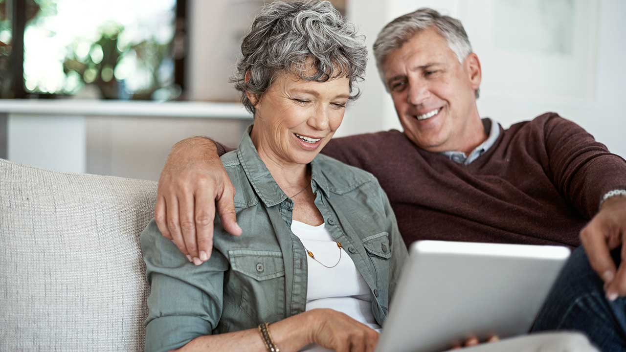 older-couple-sitting-on-the-couch-using-an-ipad