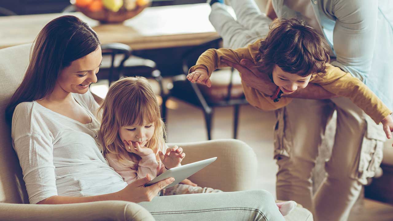 young-mother-playing-on-ipad-with-daughter-while-father-plays-with-son