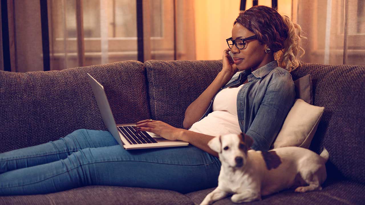young-woman-on-the-couch-with-her-dog-using-a-laptop