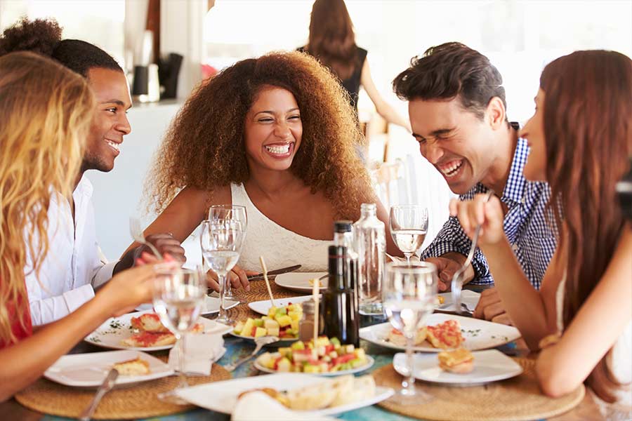 A group of friends laughing as they eat breakfast