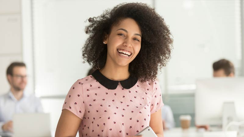 Young happy intern smiling for the camera while working