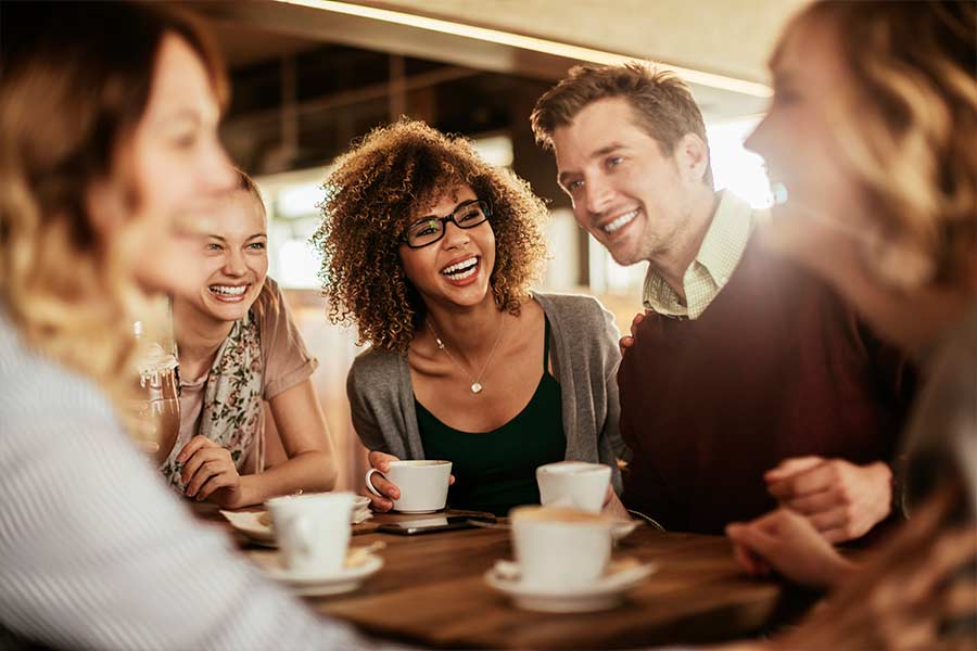 A group of friends sitting around a table at a coffee shop talking